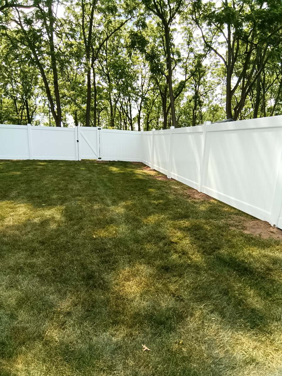 Finished white vinyl privacy fence corner with a gate
